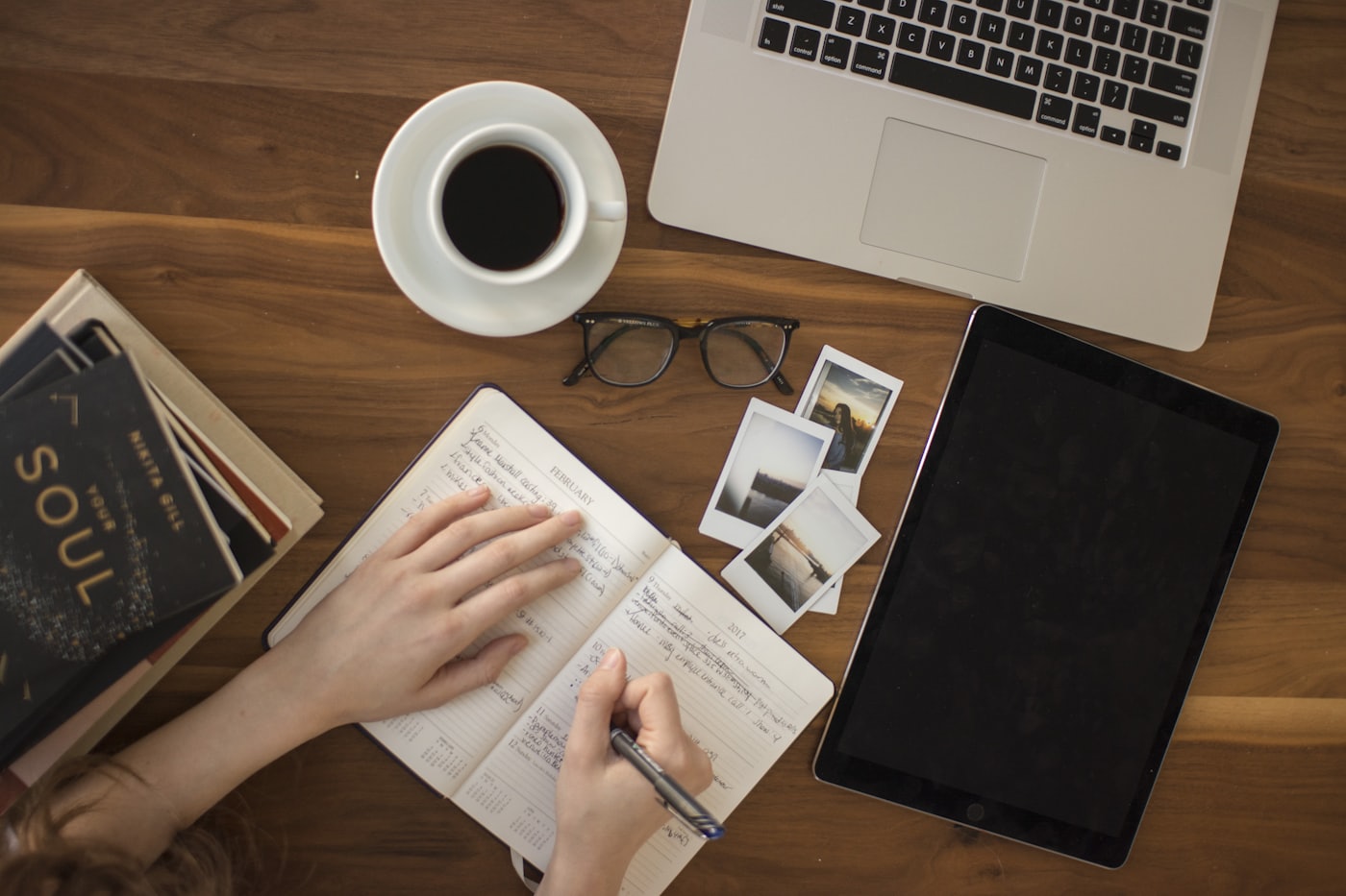 Hands writing on paper next to a laptop — editing website sentences until they sound spoken