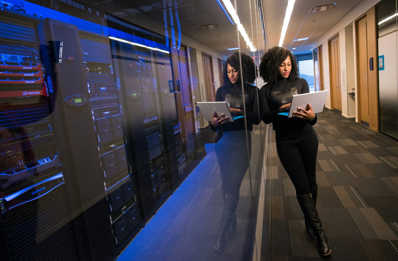 Engineer reviewing a tablet beside a glassed server room