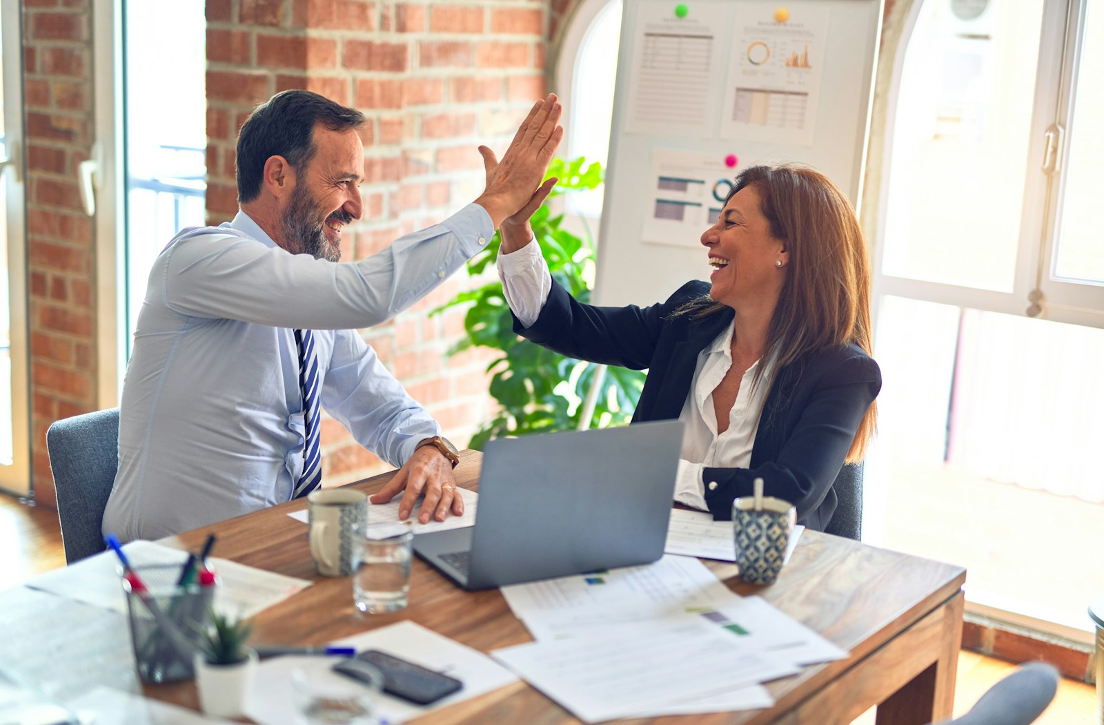 Two colleagues high-fiving after agreeing a website handover